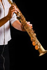 Obraz premium soprano saxophone in the hands of a girl on a black background