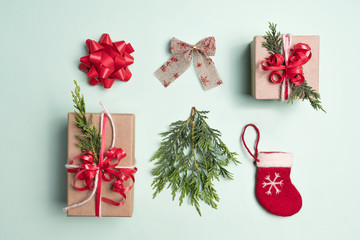 Christmas inspired flat-lay taken from above of presents, gifts, ribbon, bow, stocking and Christmas tree branch. Background colour green with Green, Red, natural colours.