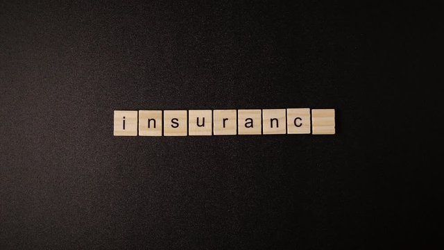 Closed Wooden cubes open and sets up a word «Insurance» on a black table