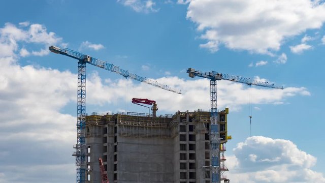 Timelapse view of skyscraper building construction with cranes on the roof.