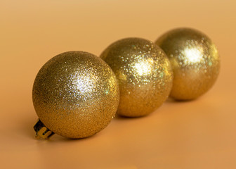 Golden shiny ball to decorate the Christmas tree for the New Year and Christmas on an orange background. Decor for the holiday..