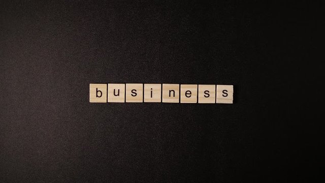 Closed Wooden cubes open and sets up a word «Business» on a black table