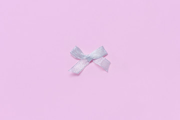 Silver Christmas bow on a light pink background