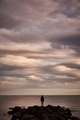 Fototapeta premium A man contemplates the Mediterranean Sea from the rocks of the Plage Baleine in Sète. France