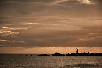 A man contemplates the Mediterranean Sea from the rocks of the Plage Baleine in Sète. France