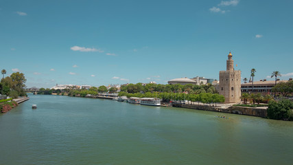 Views of the city from the bridge Puente San Telmo over Guadalquivir river towards watchtower Torre del Oro, Triana bridge and neighborhood and Cajasol Tower, in Seville, Andalusia, Spain