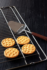 COOKIES BAKED ON OVEN GRILL AND SPOON ON BLACK PAINTED WOOD BACKGROUND