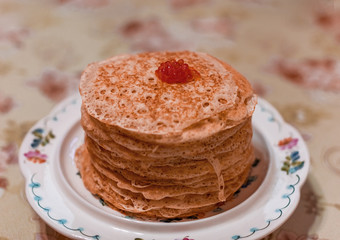 a stack of lace pancakes with red caviar lies on a porcelain stand on a table. food photo. Maslenitsa.
