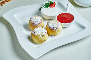 Homemade cheesecakes or Syrniki with jam and sour cream on a white plate. Ukrainian food. Breakfast food