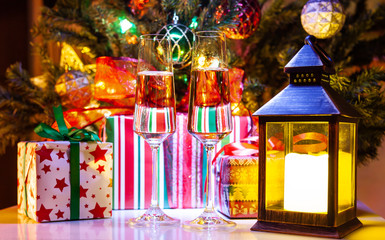 Christmas gift boxes and wine glasses of champagne near decorated Christmas tree