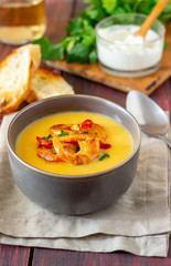 Cheese cream soup with grilled shrimp on a wooden background.