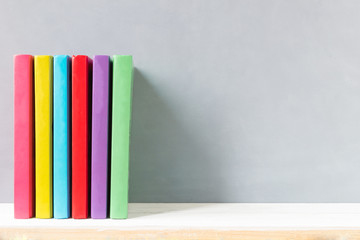 multicolour books on a wooden shelf and gray wall. with copy space