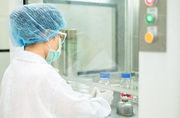 The microbiologist is testing the microbial contamination in the sample under vertical laminar air...