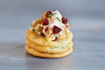 Fresh homemade cranberry cheese spread made with cream cheese, white cheddar, dried cranberries, walnuts, and chive over slate. Selective focus with blurred background 