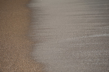 Fototapeta na wymiar wet and clean beach sand, brown