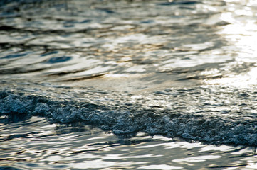 Small waves break before reaching the beach at sunset