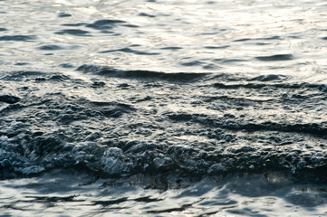 Small waves break before reaching the beach at sunset