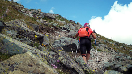 Fototapeta premium Woman skyrunner hiking in the mountains with nordic walking poles and backpacker.