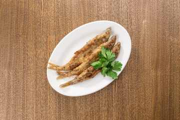 Seafood fried fish in batter on white plate isolated on wooden table