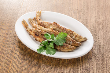 Seafood fried fish in batter on white plate isolated on wooden table