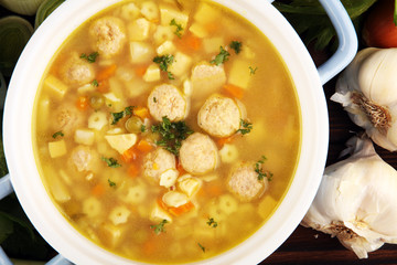 Broth with marrow dumplings and carrots, onions various fresh vegetables in a pot - colorful fresh clear spring soup. Rural kitchen scenery bouillon