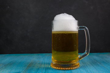 Mug of beer on wooden table on dark background