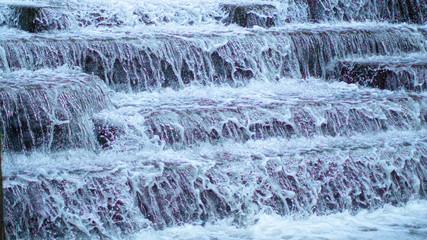 Water Cascading over Weir Steps on canal slipway showing blur blurred motion and freeze frame of water droplets for background tectures and layer effects