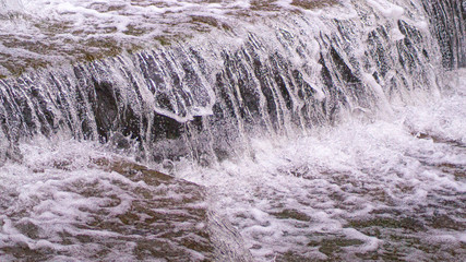 Water Cascading over Weir Steps on canal slipway showing blur blurred motion and freeze frame of water droplets for background tectures and layer effects