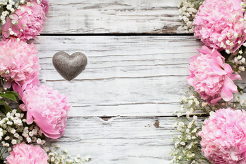 Pink Peonies, Baby's Breath flowers and heart over a white rustic wood table background  with copy space for your text. Flat lay.