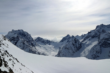 Obraz premium Snowy Mountains peaks in the clouds blue sky Caucasus