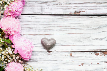 Pink Peonies, Baby's Breath flowers and heart over a white rustic wood table background  with copy...
