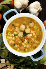 Broth with marrow dumplings and carrots, onions various fresh vegetables in a pot - colorful fresh clear spring soup. Rural kitchen scenery bouillon