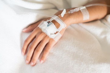 Selective focus young boy hand and set iv fluid intravenous drop saline drip on hospital bed.Medical treatment concept.