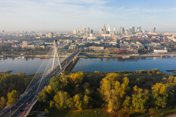 Obraz na płótnie Canvas Drone Shot. Cityscape with river and bridges in the morning in the fog. Warsaw. Poland. Aerial view of a beautiful sunrise and a river with bridges and a stadium.
