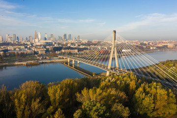 Fototapeta na wymiar Drone Shot. Cityscape with river and bridges in the morning in the fog. Warsaw. Poland. Aerial view of a beautiful sunrise and a river with bridges and a stadium.