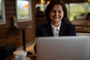 Fototapeta na wymiar Beautiful Senior Businesswoman is working in the Cafe