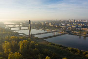 Drone Shot. Cityscape with river and bridges in the morning in the fog. Warsaw. Poland. Aerial view of a beautiful sunrise and a river with bridges and a stadium.