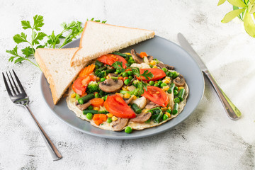 Omelet with vagetable, tomatoes, mushrooms,green beans, corn, sourdough toast isolated on white marble background. Homemade food. Tasty breakfast. Selective focus. Hotizontal photo.