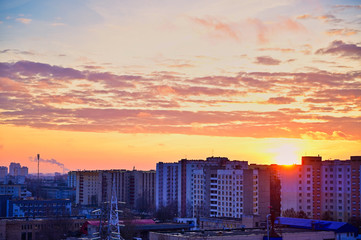 The concept of sunset in the evening sky over the city. Photo of the evening sun over houses in a modern area.