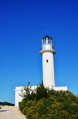 Fototapeta na wymiar Lefkada island, Greece. 10/21/2019. white lighthouse and green trees on the edge of Lefkada island