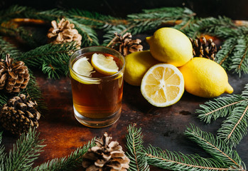 Cup of tea with lemon fruit lemons with fir branches for a rustic background. Natural food.