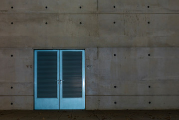 Very simple concrete facade with a double door, concrete wall with a door