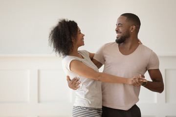 Happy biracial couple have fun dancing together at home