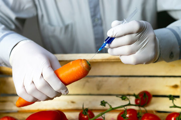 Chemical processing of vegetables, fertilizers and GMOs. A man injects chemicals into carrots, GMO...