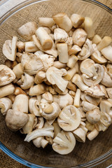 Close up shot of cut forest champignon mushrooms in glass bowl standing on table covered with sackcloth. Vegetarian, organic and healthy food. Eating habits, nutrition and diet concept.