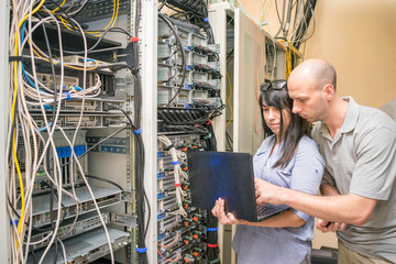 Man and woman set up network equipment in the server room. Teamwork concept in the field of information technology. A team of experts working near the computer racks datacenter