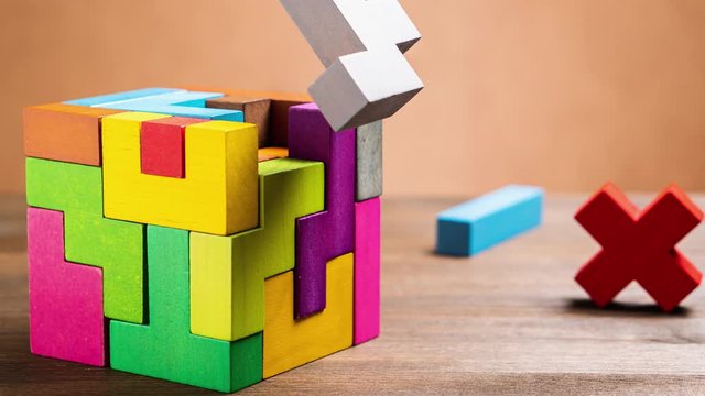 Missed items are setting in the colorful wooden cube puzzle on the brown table. stop motion.