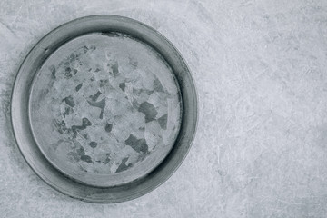 Empty round metal plate on gray concrete background, top view,