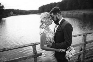 Black and white foto stylish couple of newlyweds posing on a bridge on wedding day. Handsome...