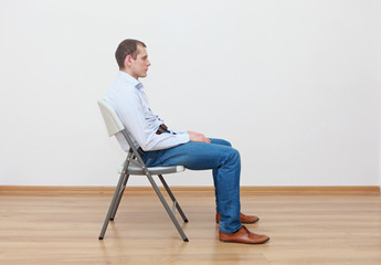 caucasian man sitting on  chair in incorrect  position